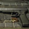 Glock 34 Gen 5 MOS long-slide pistol side profile resting on a bullet vest backgound with 9mm alongside