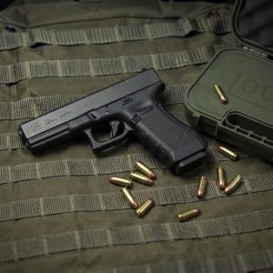 Glock 22 Gen 3 .40 S&W pistol side profile resting on a neutral background along side it case and some 9mm luger bullets